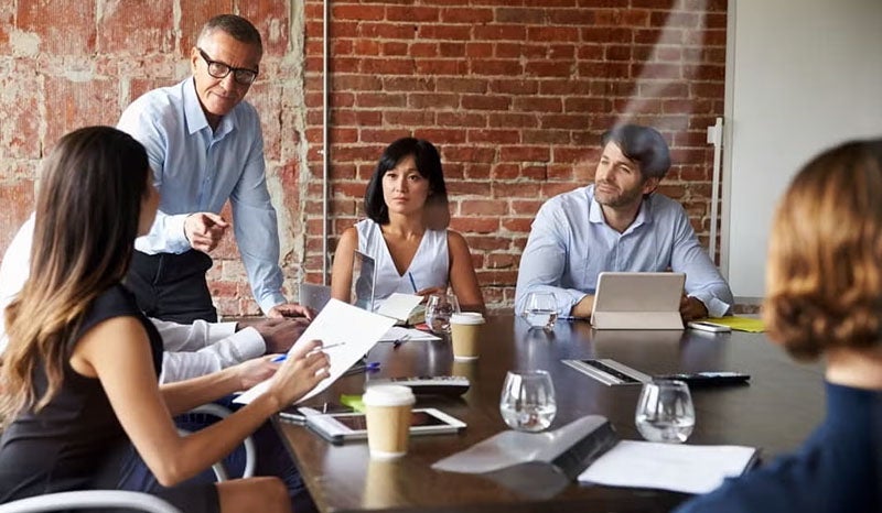 A group of people engaged in a business discussion in a modern office with exposed brick.