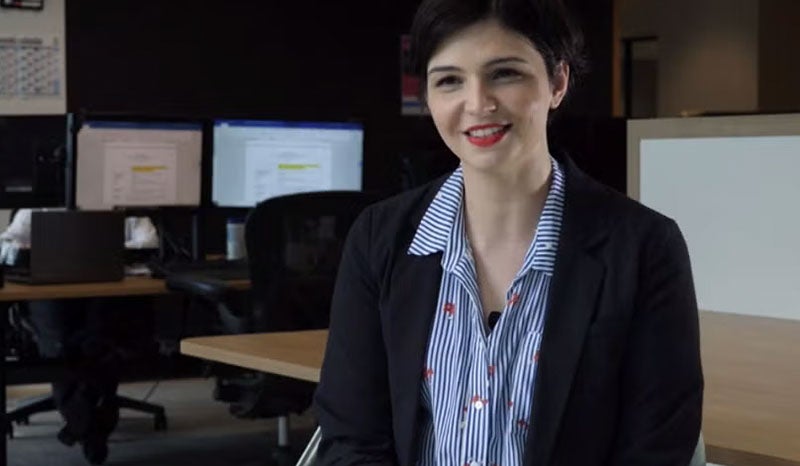A woman smiling and talking in an office setting, preparing for an interview.