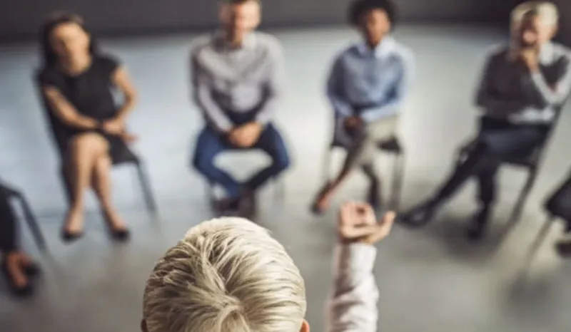 A person presenting to a group of colleagues during a meeting in a modern office.
